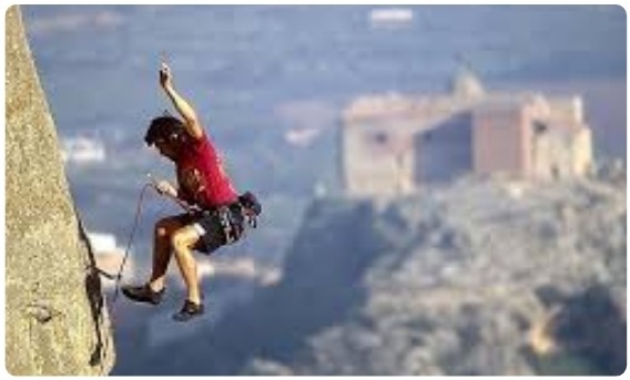 Arrampicatore in movimento dinamico con vista su un borgo